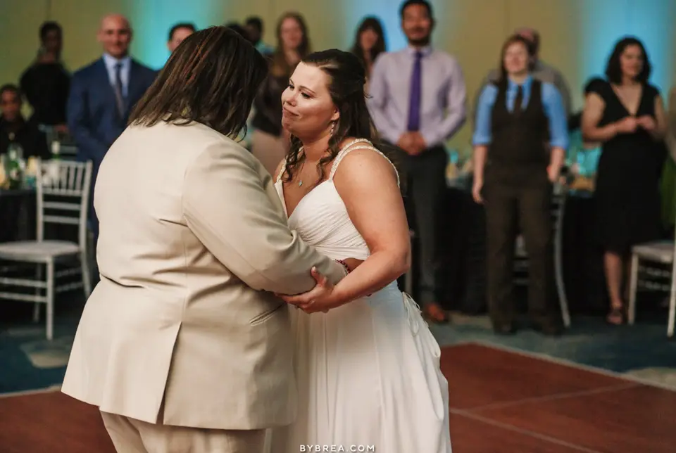 Newlyweds sharing a slow dance while guests watch from the edge of the floor