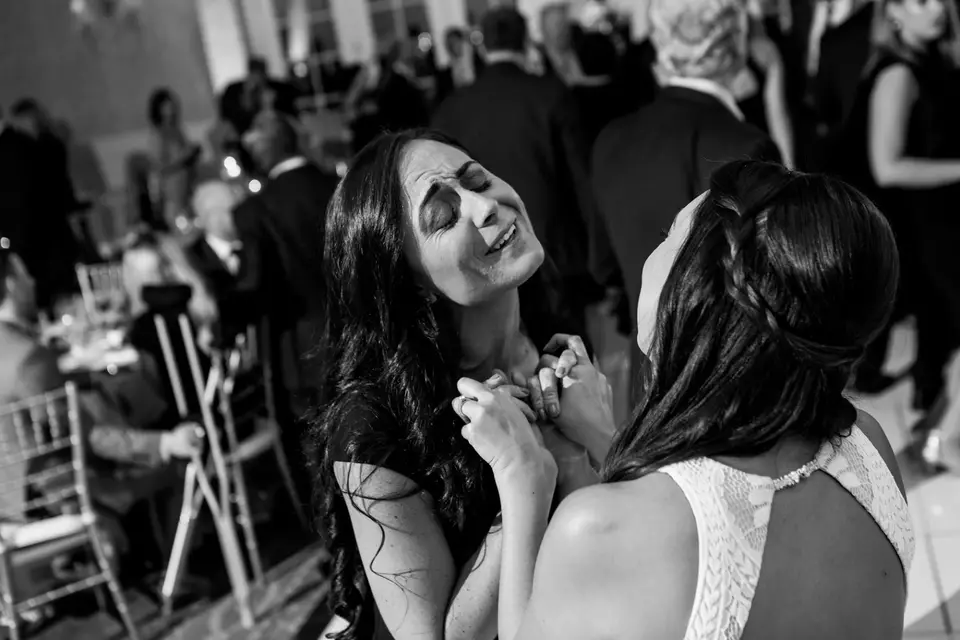 Black and white photo of two women embracing on the dance floor, one with her eyes closed and smiling