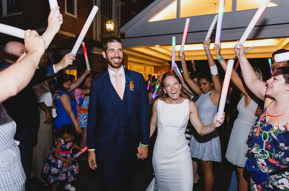 Bride and groom exiting through a line of guests holding glow sticks at night