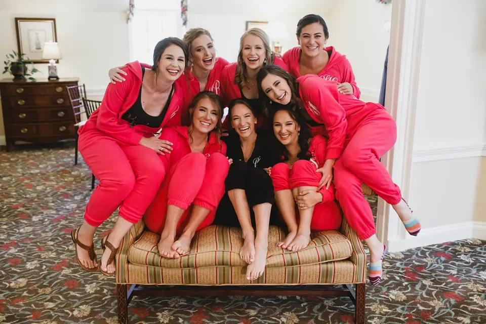 Bridal party in matching pink pajamas posing together on a striped bench