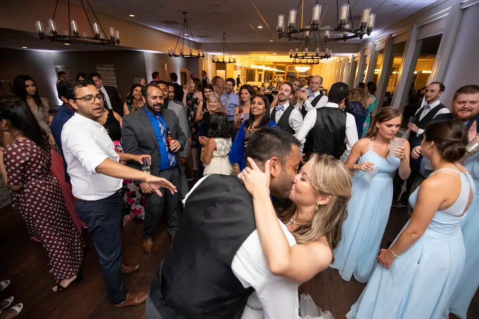 Bride and groom embracing on a crowded dance floor as bridesmaids and guests dance around them