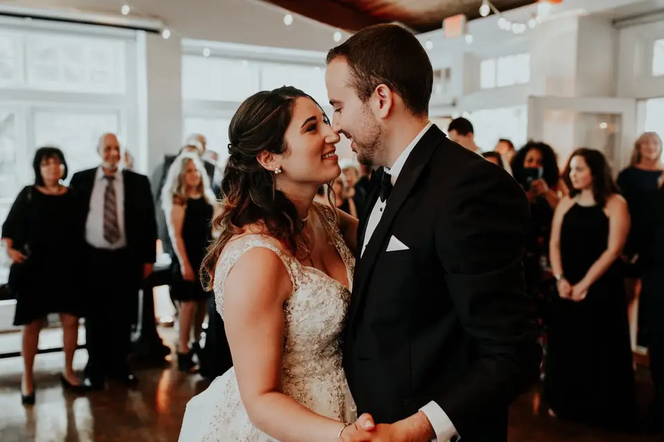 Zephan and Mollye in a first dance, smiling close together as guests watch behind them