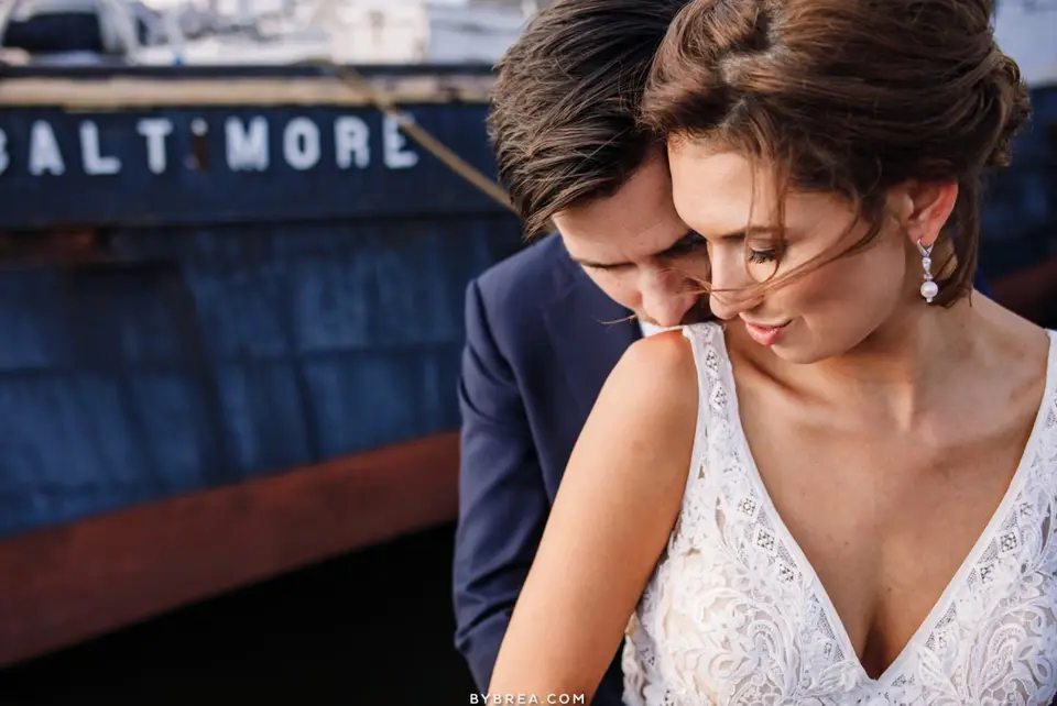Close-up of bride and groom embracing in front of a ship with Baltimore lettered on its hull