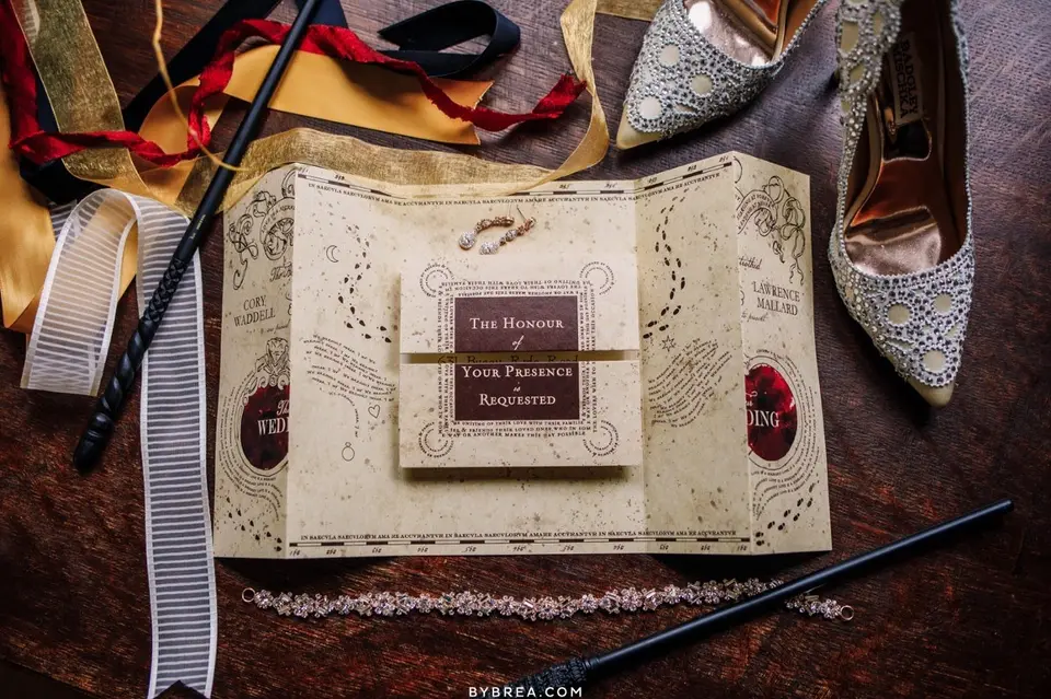 Wedding invitation styled like a map with wands, ribbons and sparkly heels on a wooden table