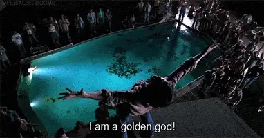 Movie still of a person leaping toward a lit pool with a crowd watching, caption I am a golden god!