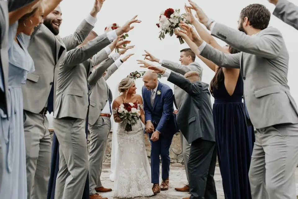 Bride and groom walking through an archway of arms made by the wedding party and guests