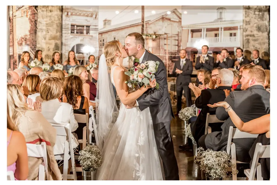 Bride and groom kissing in the aisle as seated guests look on