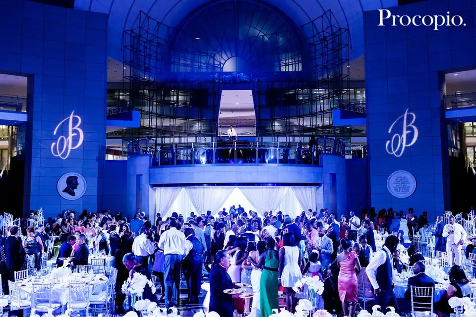 Crowded ballroom dance floor with guests dancing under blue lighting and monogram projections on the walls