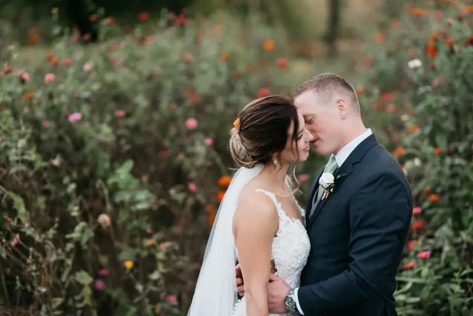 Bride and groom embracing among pink and orange flowers in a garden