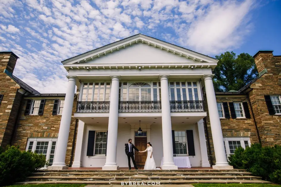 Bride and groom stand on the steps of Glenview Mansion beneath its tall white columns