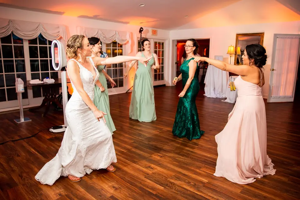 Bride and bridesmaids dancing on a wood floor in a reception room