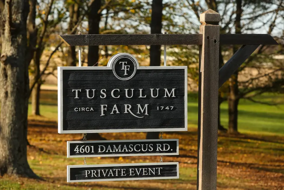 Wooden Tusculum Farm sign reading 4601 Damascus Rd., Private Event, with fall trees behind