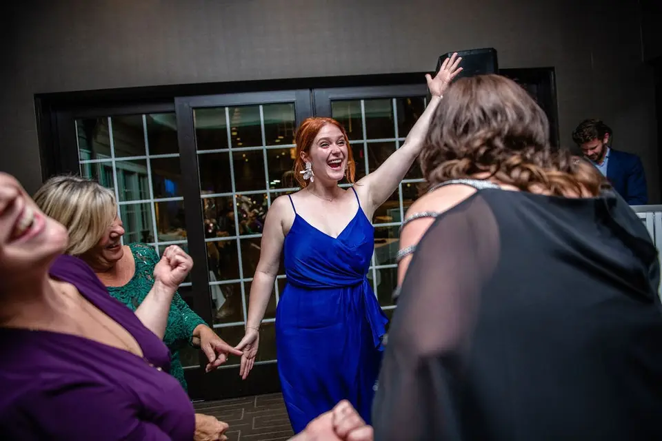 Laughing woman with red hair in a blue dress dancing among other guests