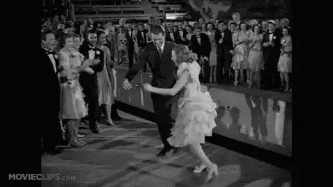 Black and white film clip of a couple dancing energetically as a crowd watches, MovieClips watermark