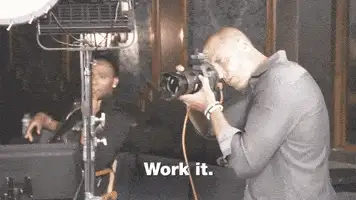 Man with a camera and the caption 'Work it.' with another person behind a studio light