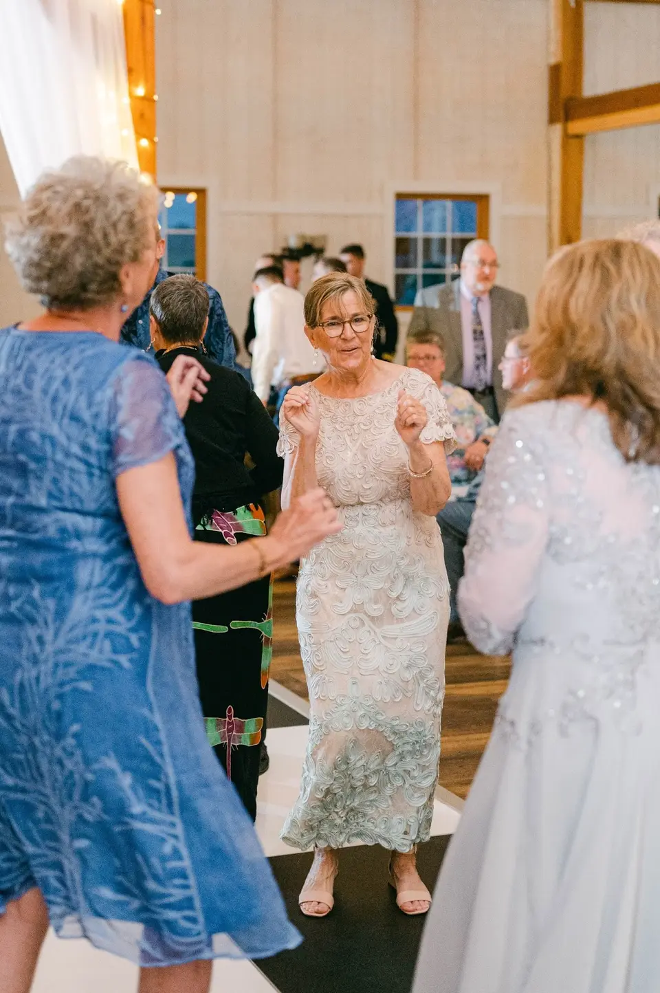 Older women in lace and blue dresses dancing on a barn dance floor at the Shadow Creek reception