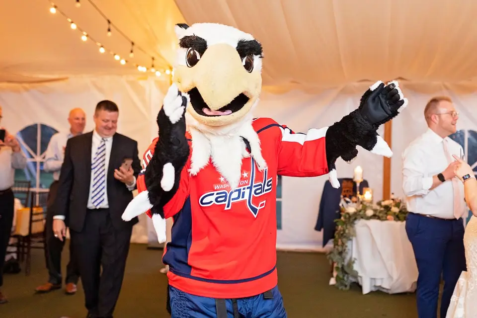 Washington Capitals mascot in a red jersey dancing with guests at a tent reception