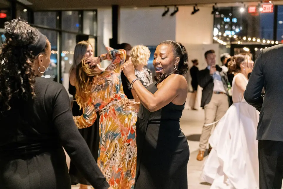 Guests dancing at a city-view reception while the bride in her white gown moves through the crowd
