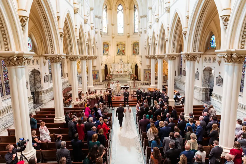 Bride and groom standing at the altar of a large church as guests fill the pews during the ceremony
