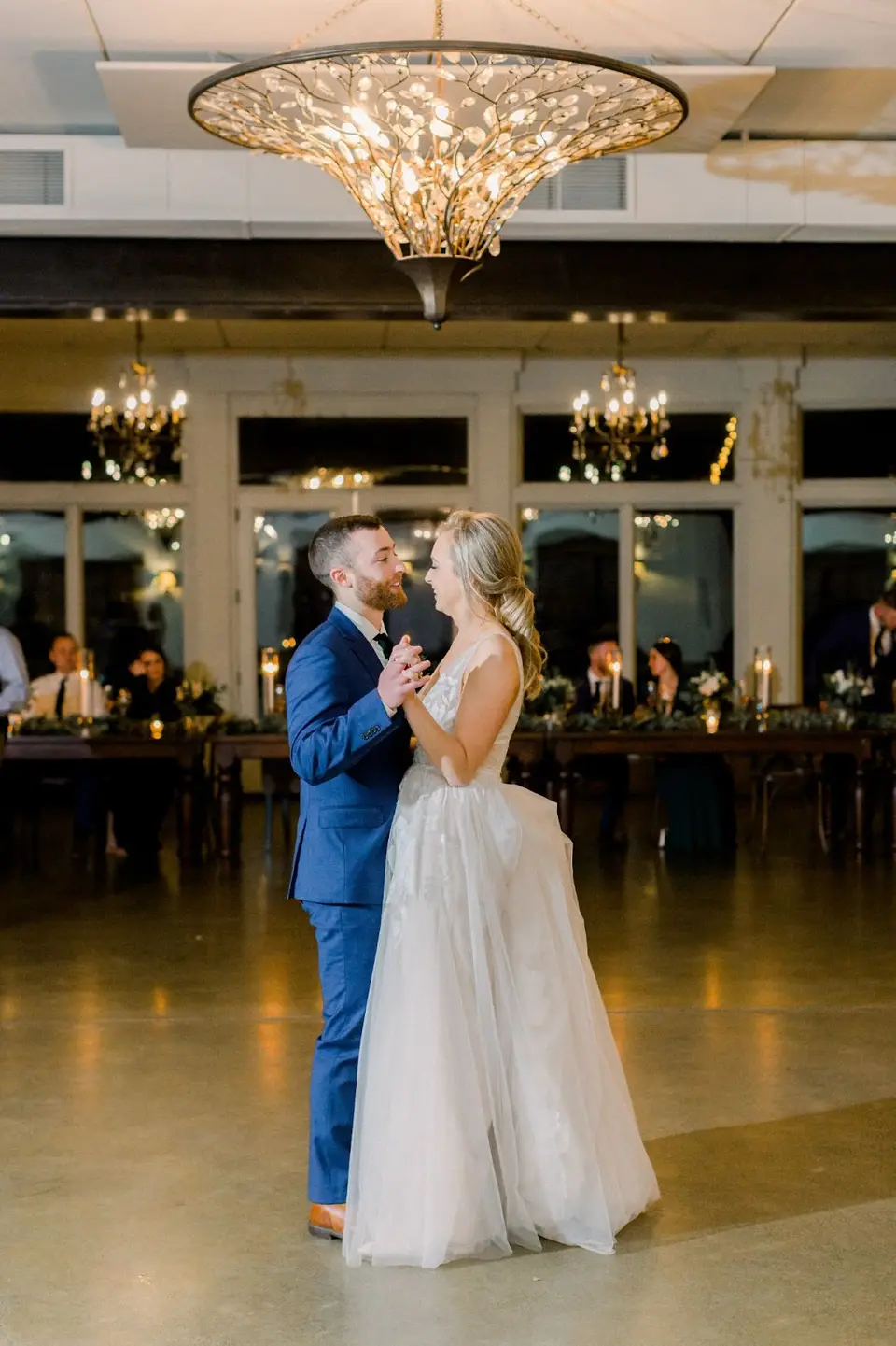 Bride and groom dancing their first dance beneath a crystal chandelier