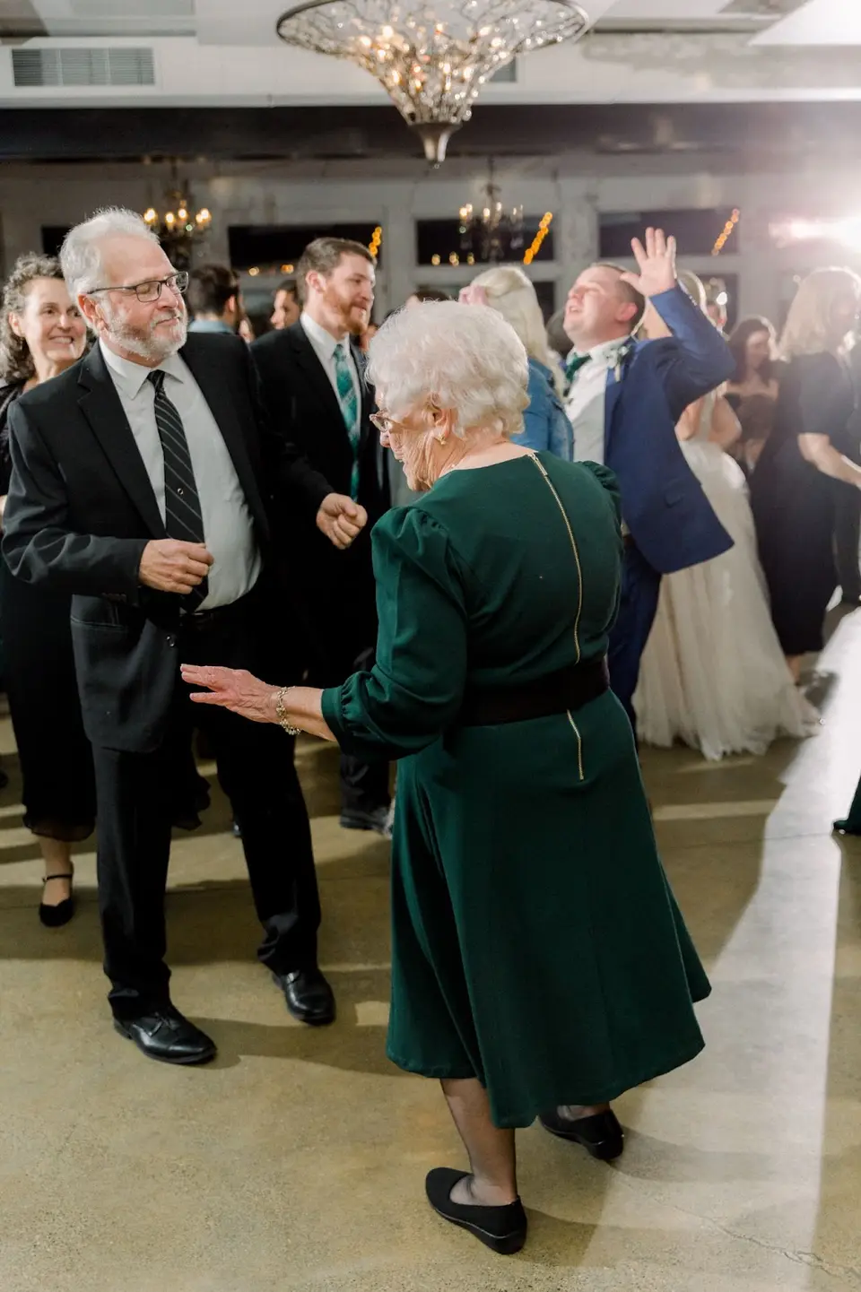Older woman in a green dress dancing as other guests dance behind her