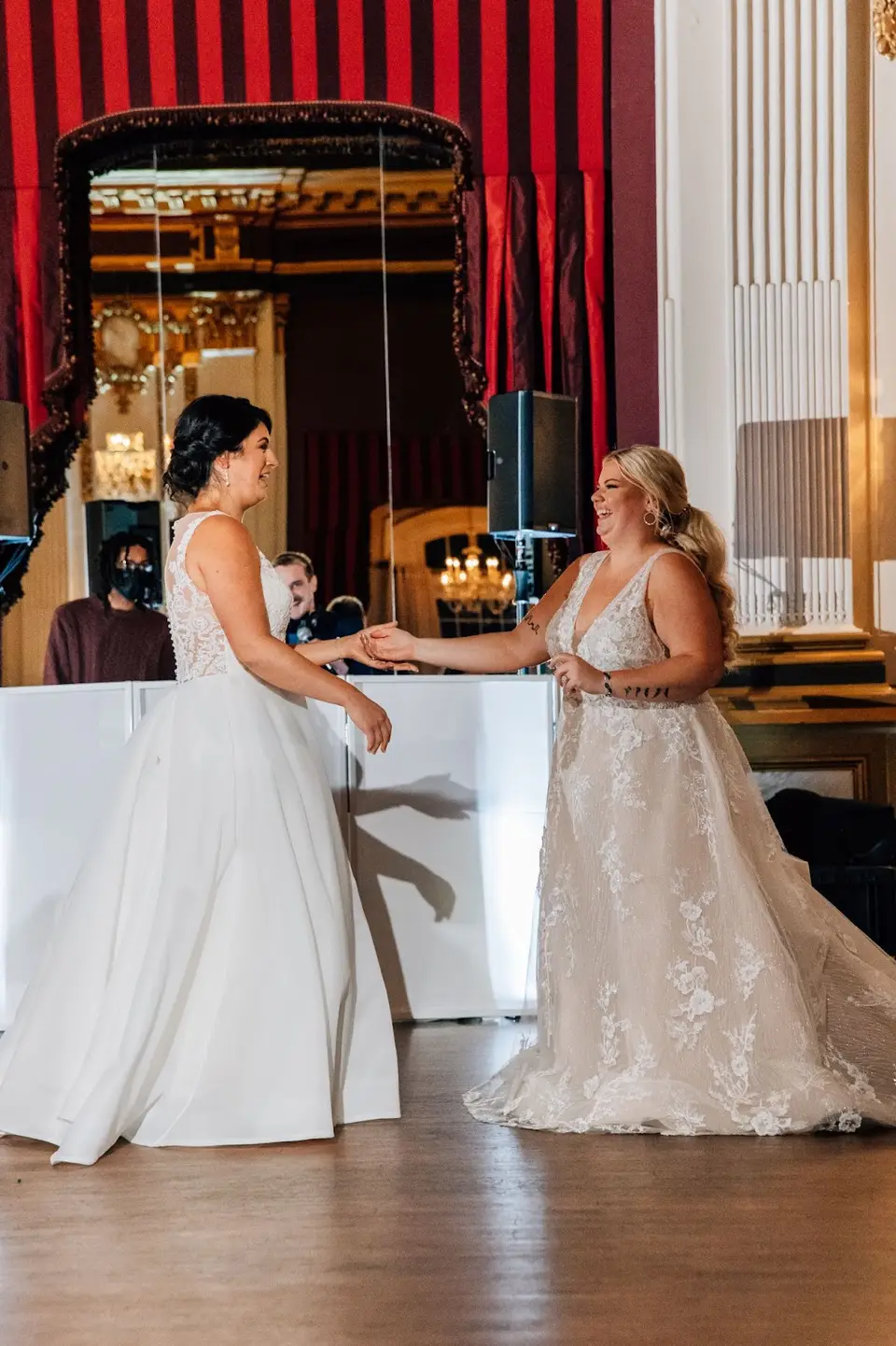 Two brides dancing together on the ballroom dance floor near the DJ booth