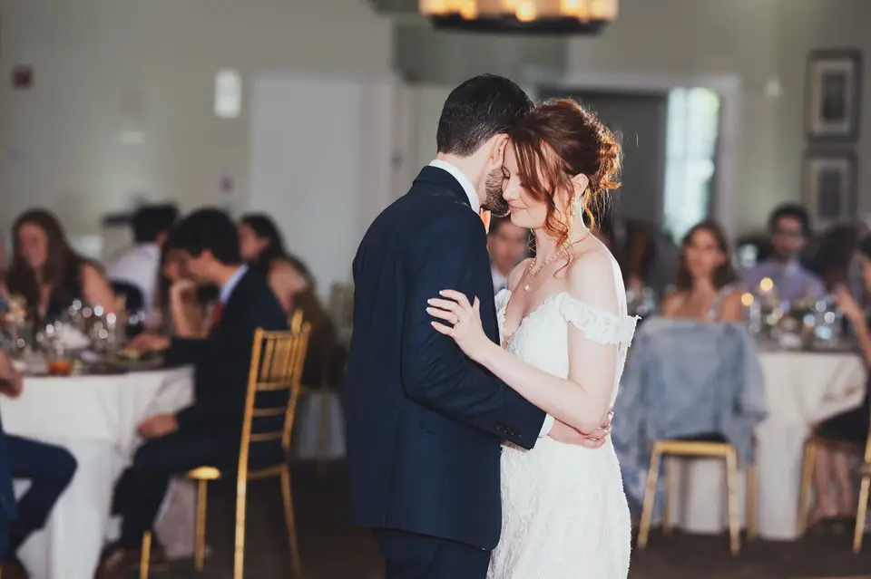 Natasha and Ben slow dancing at their reception while seated guests look on