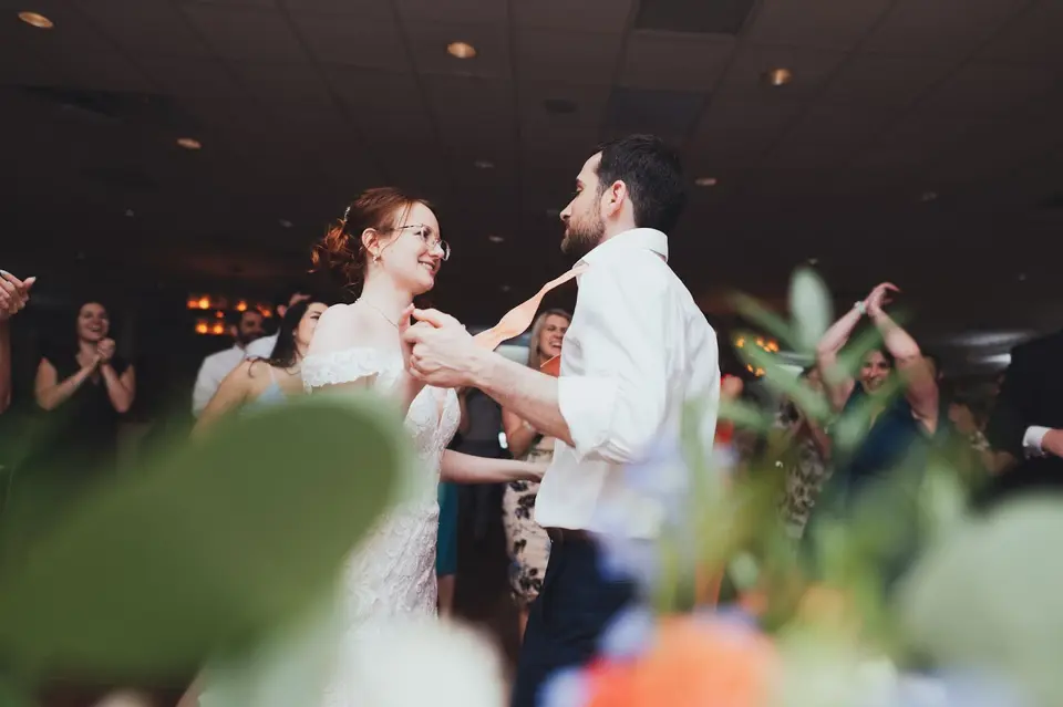 Natasha and Ben dancing close with orange and blue flowers blurred in the foreground