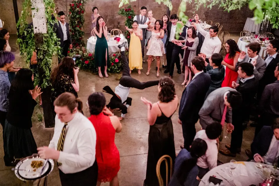 Guest does a floor spin move on the dance floor while onlookers clap and cheer