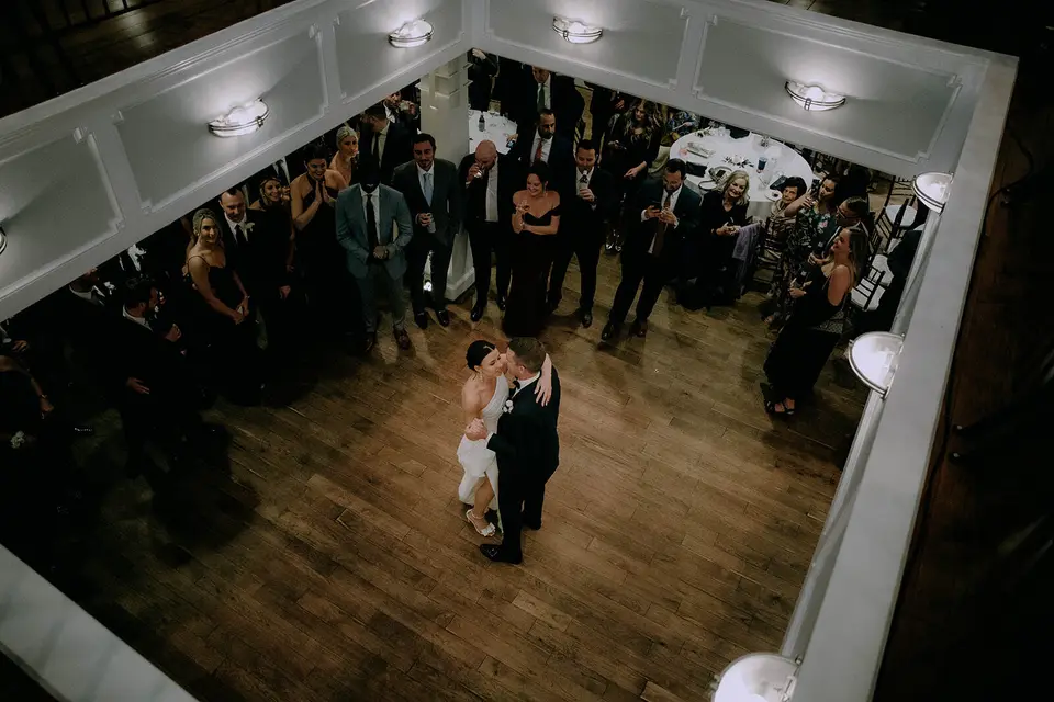 Bride and groom smiling at each other during their first dance as guests watch