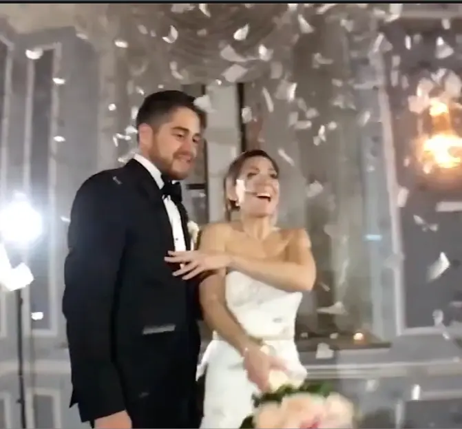 Bride and groom smiling as confetti falls around them in a ballroom