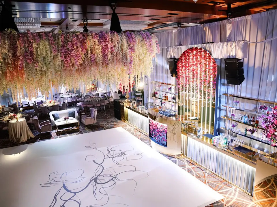 Ballroom with hanging floral canopy, white dance floor and illuminated bar