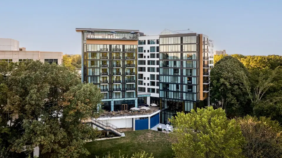 Modern hotel building with glass balconies and trees in front on a clear day
