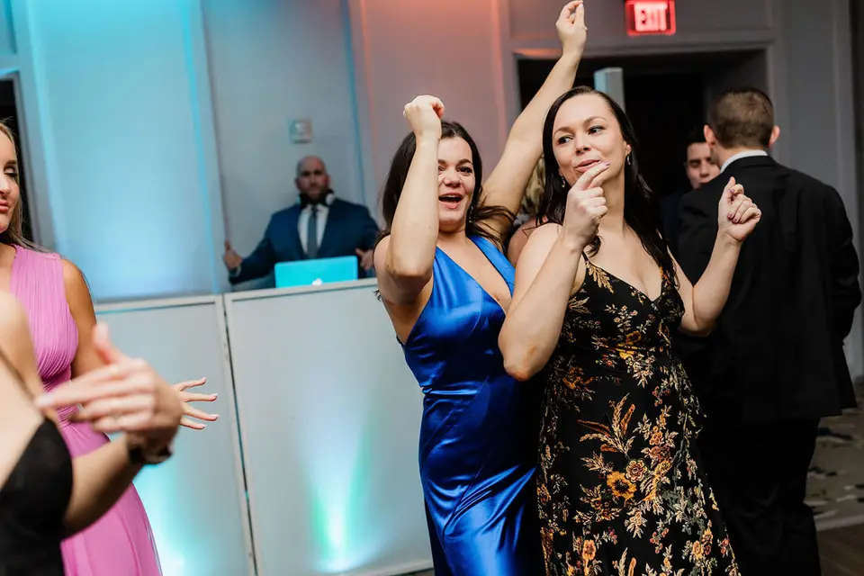 Guests in colorful dresses dancing near a white DJ booth with the DJ behind it