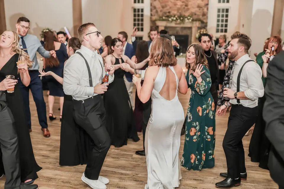 Guests dancing at the reception, including a man in sunglasses and suspenders and a woman in a satin dress