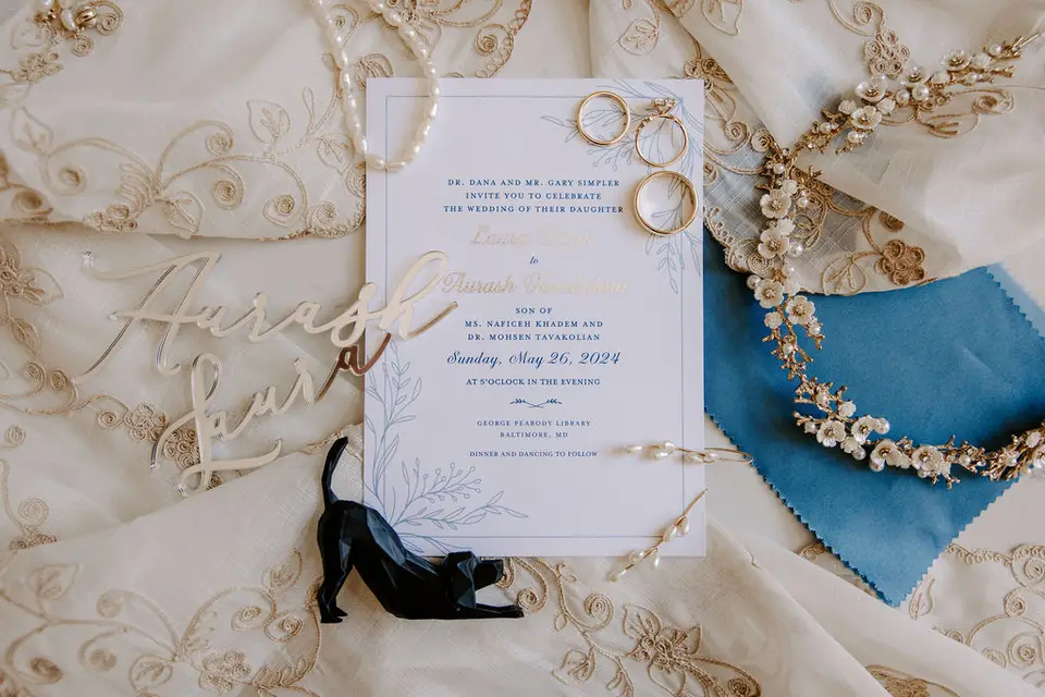 Wedding invitation with rings, pearls, blue fabric and gold name signs on lace for Laura and Aurash