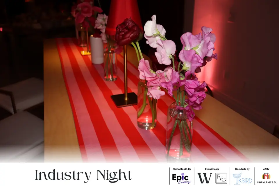 Pink flowers in glass vases on a red and white striped table runner at Industry Night