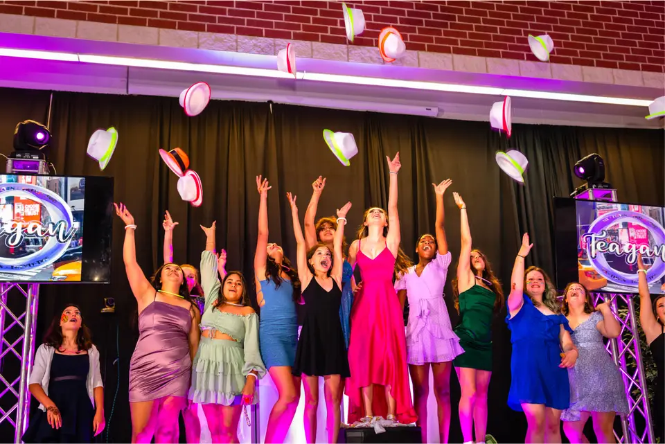 Image of teenage girls throwing up their colorful hats in the air